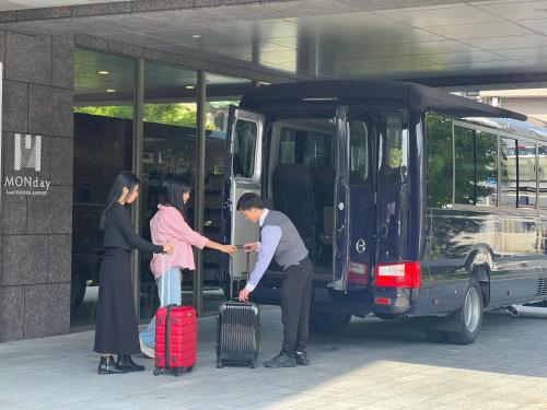um grupo de pessoas saindo de um ônibus com bagagem em hotel MONday Haneda Airport em Tóquio