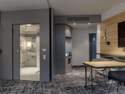a dining room with a table and a kitchen at Novotel Suites Berlin City Potsdamer Platz in Berlin