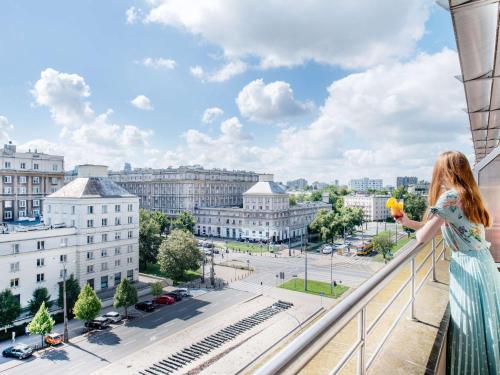 a woman standing on a balcony looking out at the city at Ibis Warszawa Stare Miasto in Warsaw
