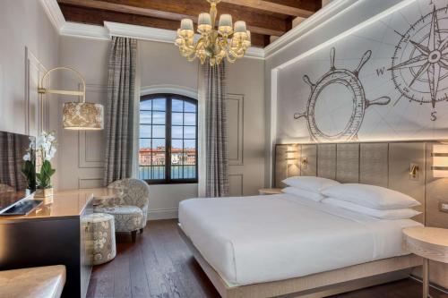 Un dormitorio con una gran cama blanca y una lámpara de araña. en Hilton Molino Stucky Venice, en Venecia