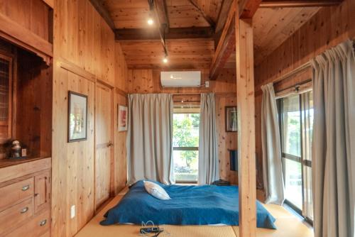 a bedroom with a bed in a room with a window at 田舎の静かな古民家の悠水居 in Itoman