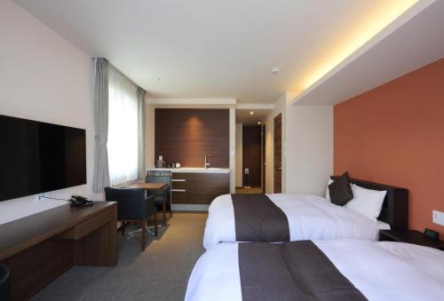 a hotel room with two beds and a desk at HOTEL PROMOTE HIROSHIMA in Hiroshima