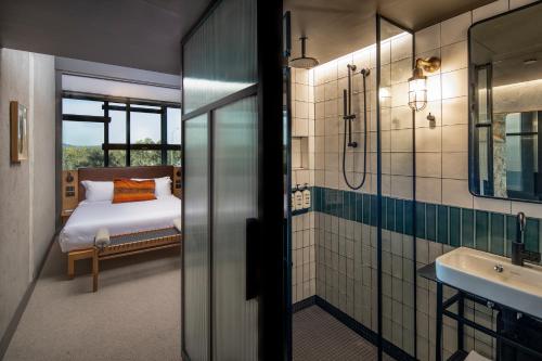 a bathroom with a bed and a shower and a sink at Ovolo Nishi in Canberra