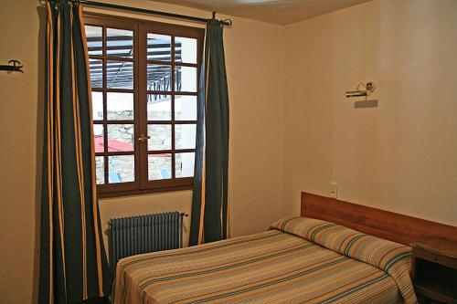 a bedroom with a bed and a large window at Hotel La Belle Aude in Matemale
